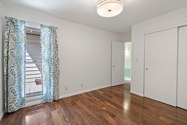 unfurnished bedroom featuring wood finished floors, baseboards, and multiple windows