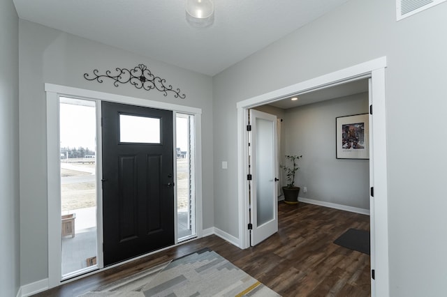 entrance foyer featuring baseboards, visible vents, and dark wood-style flooring