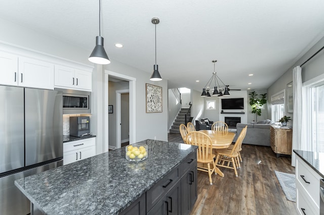 kitchen featuring white cabinetry, stainless steel appliances, a kitchen island, dark wood-style floors, and a glass covered fireplace