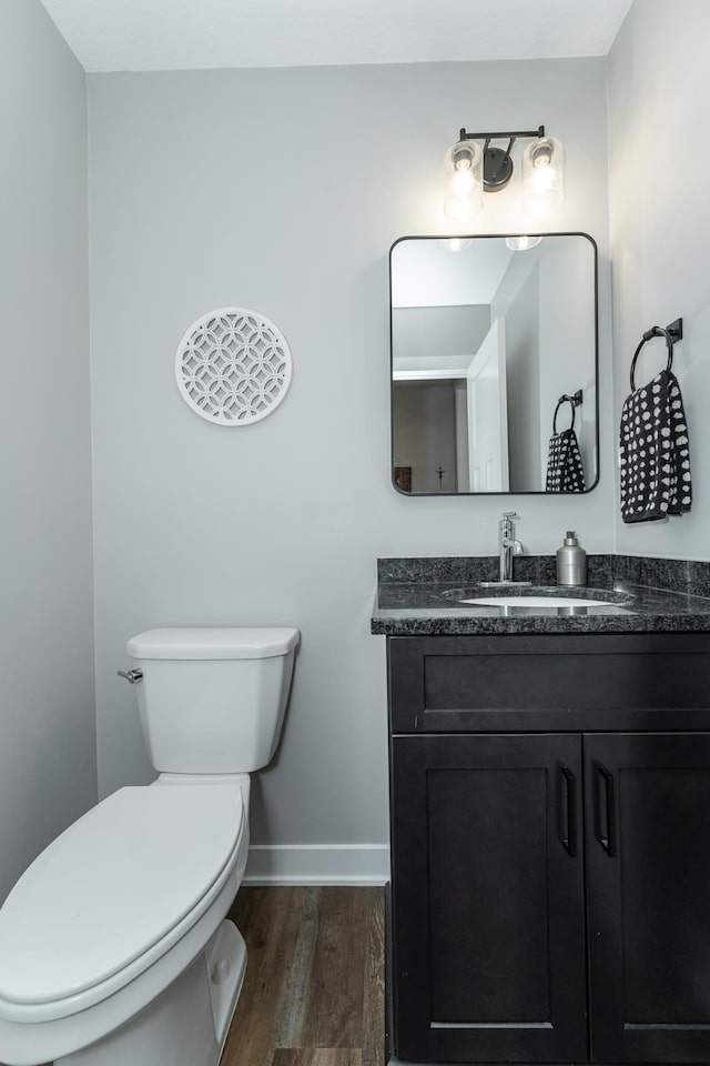 bathroom featuring toilet, vanity, wood finished floors, and baseboards