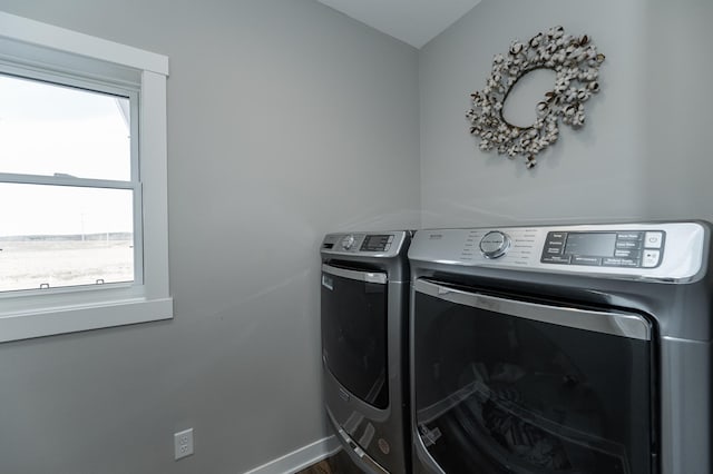 clothes washing area featuring separate washer and dryer, laundry area, and baseboards