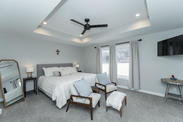 carpeted bedroom featuring recessed lighting, ceiling fan, baseboards, and a tray ceiling