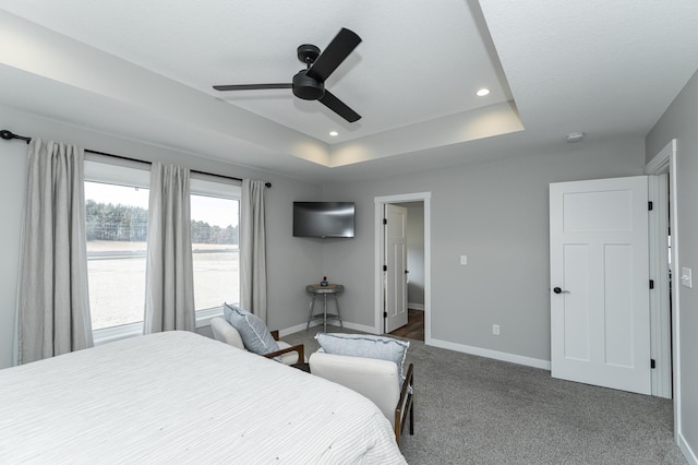 bedroom with dark carpet, ceiling fan, a tray ceiling, baseboards, and recessed lighting
