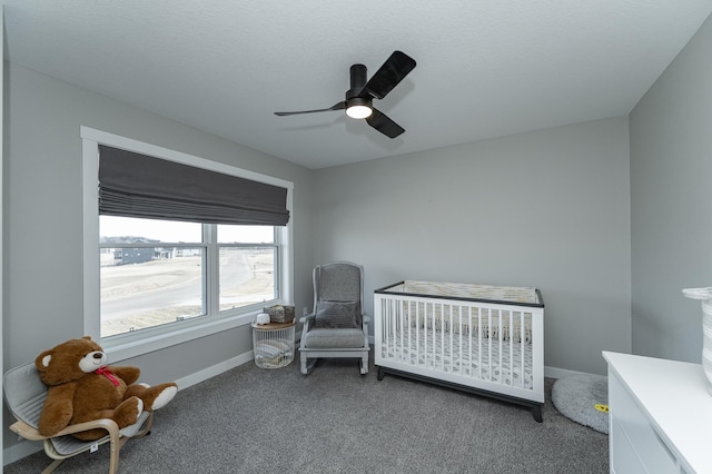 carpeted bedroom with a ceiling fan, a nursery area, and baseboards