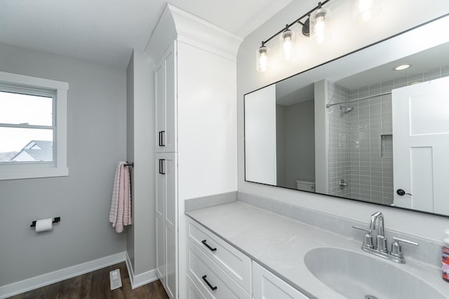 bathroom featuring baseboards, walk in shower, toilet, wood finished floors, and vanity