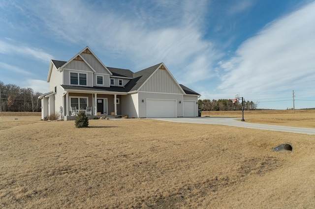 view of front of property with board and batten siding, covered porch, a garage, a front yard, and concrete driveway