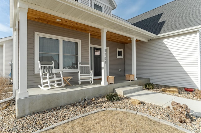 property entrance featuring roof with shingles and a porch