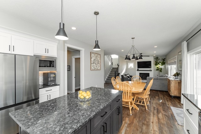 1261 Skyview Cir NW, Rochester, MN 55901 - kitchen with appliances with stainless steel finishes, a glass covered fireplace, white cabinetry, dark wood-style floors, and a kitchen island