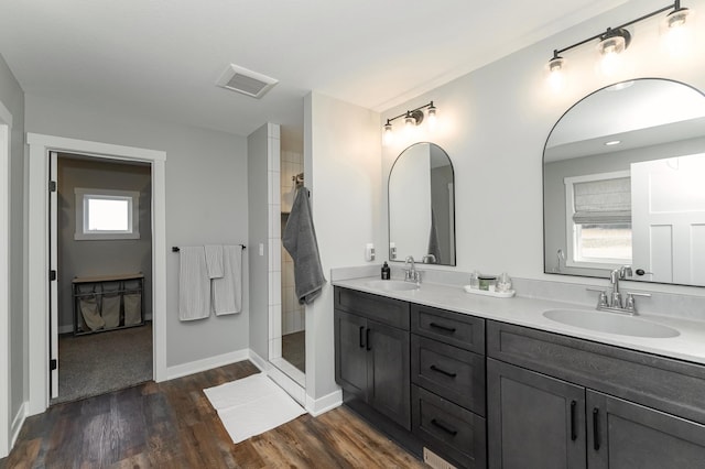 1261 Skyview Cir NW, Rochester, MN 55901 - bathroom featuring double vanity, a tile shower, wood finished floors, and baseboards