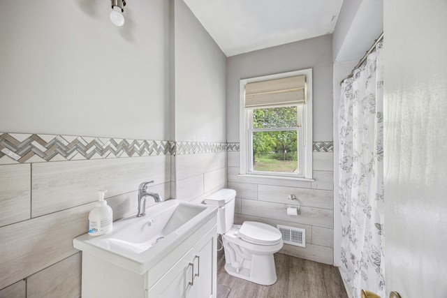 810 57th Ave N, Brooklyn Center, MN 55430 - full bath featuring tile walls, toilet, vanity, wood finished floors, and a wainscoted wall