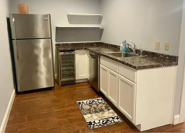 kitchen with stainless steel appliances, wine cooler, a sink, white cabinets, and dark wood finished floors