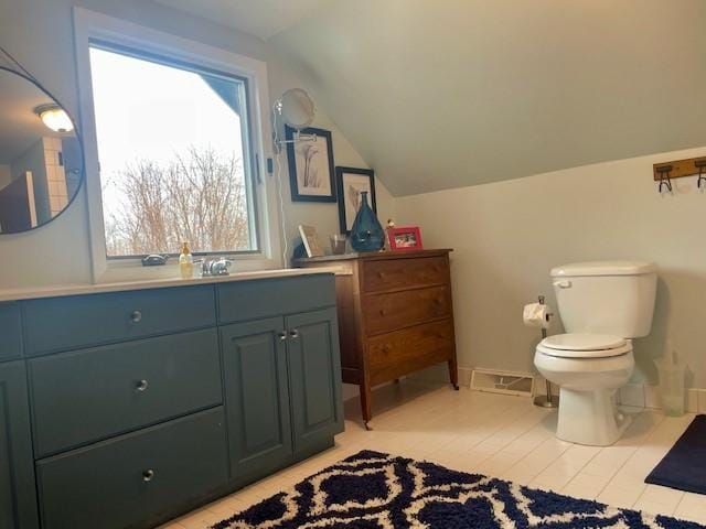 bathroom featuring lofted ceiling, toilet, vanity, tile patterned flooring, and baseboards