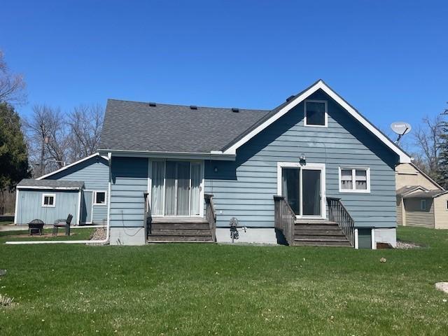 bungalow with entry steps, a front yard, and a shingled roof