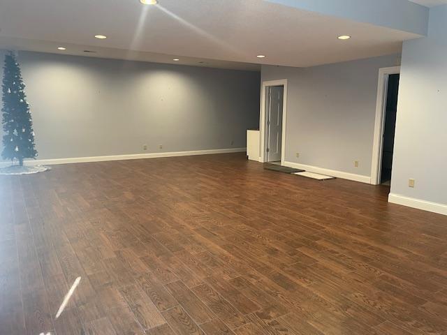 basement featuring baseboards, dark wood finished floors, and recessed lighting
