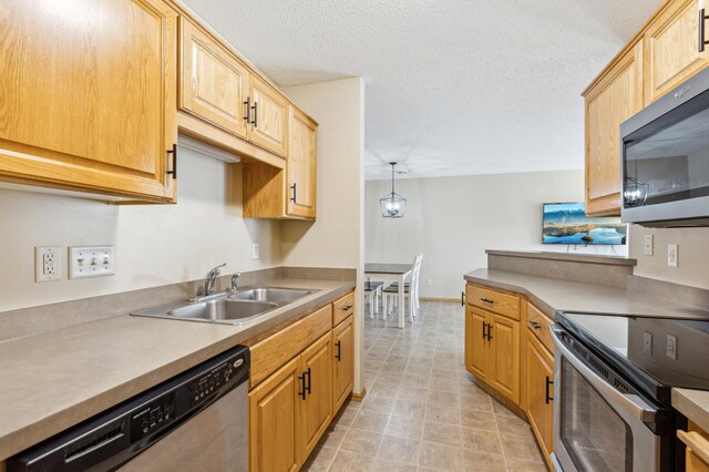 kitchen with a sink, a textured ceiling, appliances with stainless steel finishes, and light countertops
