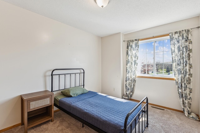 carpeted bedroom with baseboards, a textured ceiling, and visible vents
