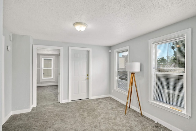 interior space with baseboards, carpet floors, and a textured ceiling