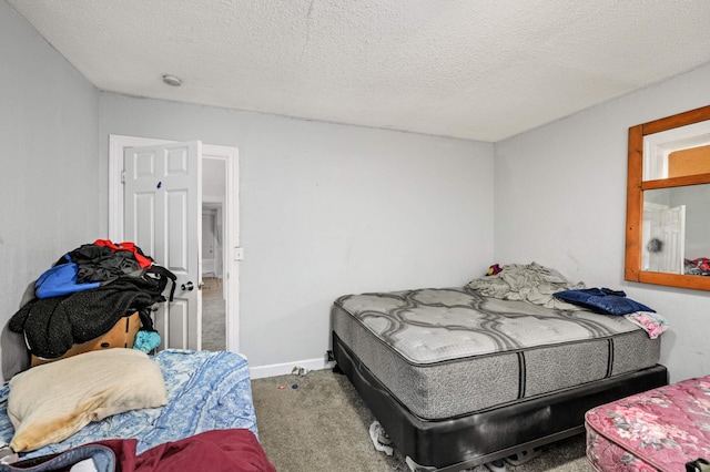 bedroom with a textured ceiling, baseboards, and carpet floors