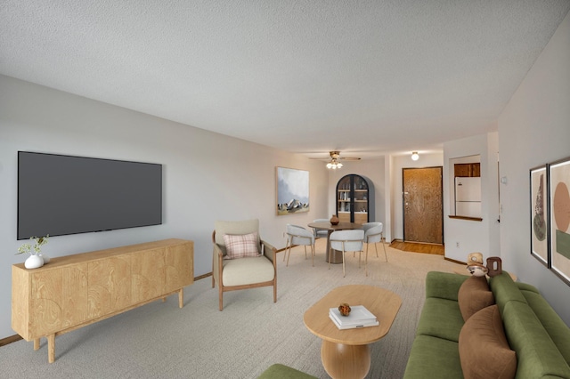 living area with ceiling fan and a textured ceiling