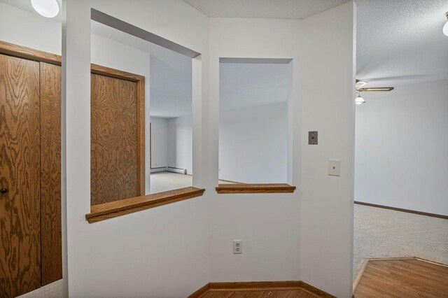 corridor with baseboards and a baseboard heating unit