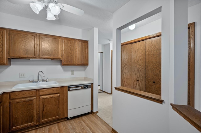 kitchen with brown cabinets, a sink, light countertops, dishwasher, and light wood finished floors