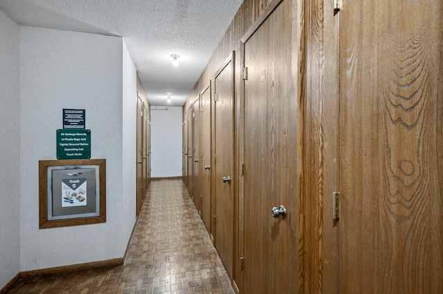 corridor featuring a textured ceiling and baseboards