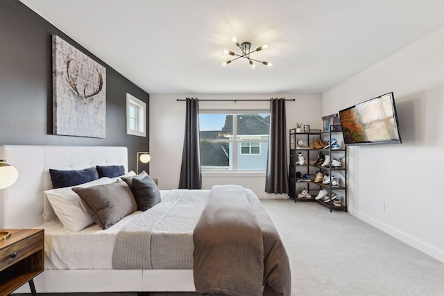 carpeted bedroom featuring a notable chandelier and baseboards