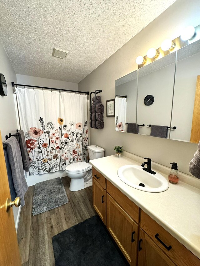 606 Tenth St W, Park Rapids, MN 56470 - full bathroom featuring wood finished floors, a textured ceiling, toilet, vanity, and a shower with curtain
