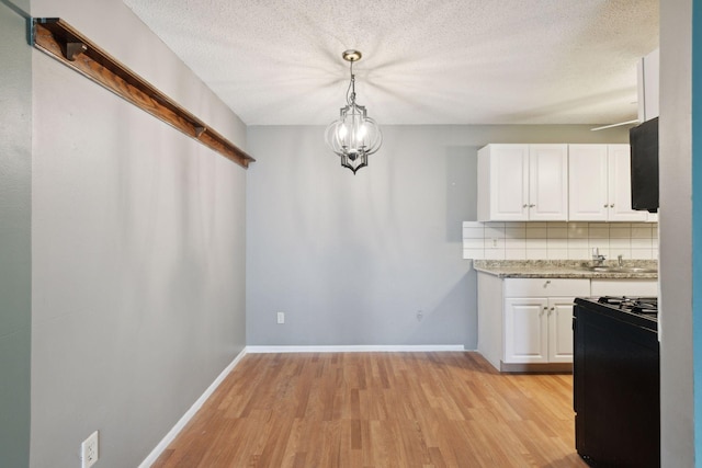 kitchen featuring white cabinets, light countertops, gas stove, and light wood-type flooring