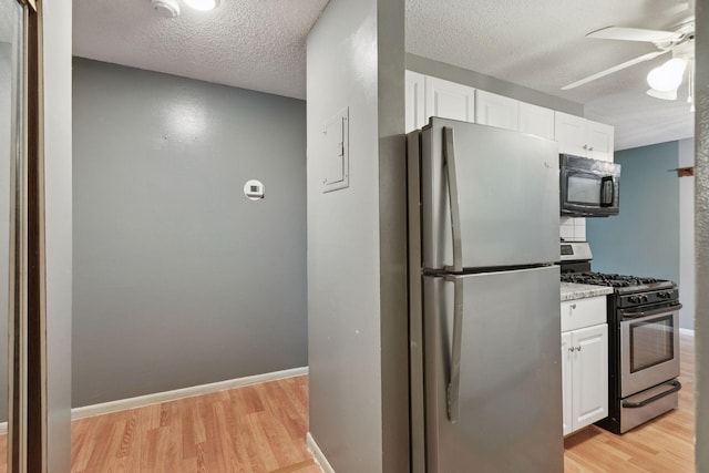 kitchen featuring a ceiling fan, stainless steel appliances, light wood-type flooring, and white cabinetry