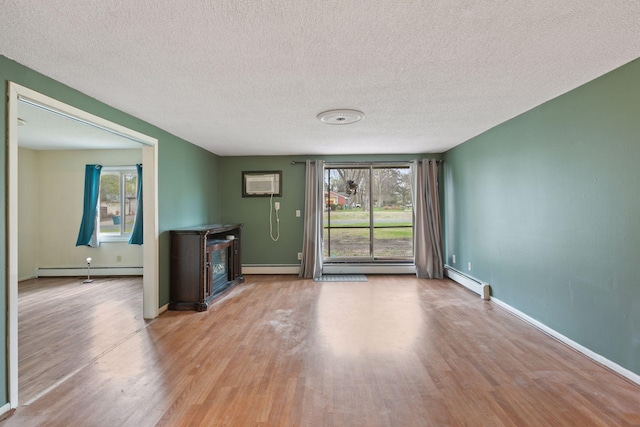 unfurnished living room with a textured ceiling, baseboard heating, and wood finished floors
