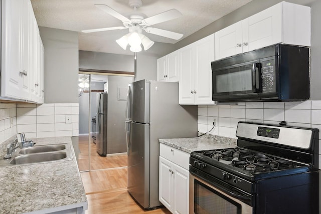 kitchen with a sink, light countertops, stainless steel appliances, a ceiling fan, and white cabinetry