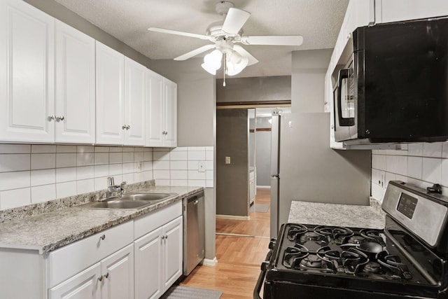 kitchen with a sink, white cabinets, a ceiling fan, light wood finished floors, and appliances with stainless steel finishes