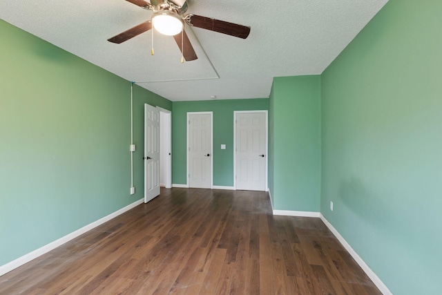 spare room with a textured ceiling, attic access, a ceiling fan, baseboards, and wood finished floors