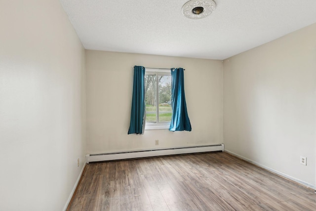 empty room featuring baseboards, a baseboard heating unit, and wood finished floors