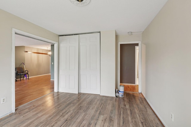 unfurnished bedroom featuring baseboards, wood finished floors, and a closet