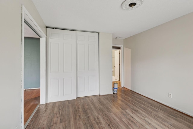 unfurnished bedroom with baseboards, wood finished floors, and a closet