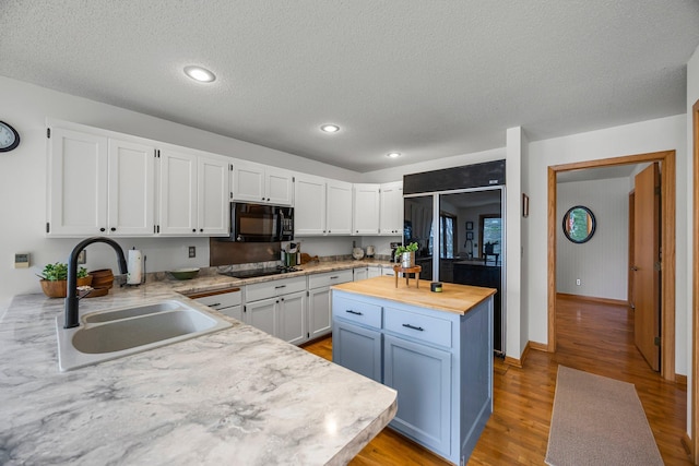 1171 County Rd E, Scott Twp, WI 54801 - kitchen featuring a sink, light wood finished floors, butcher block countertops, white cabinetry, and black appliances