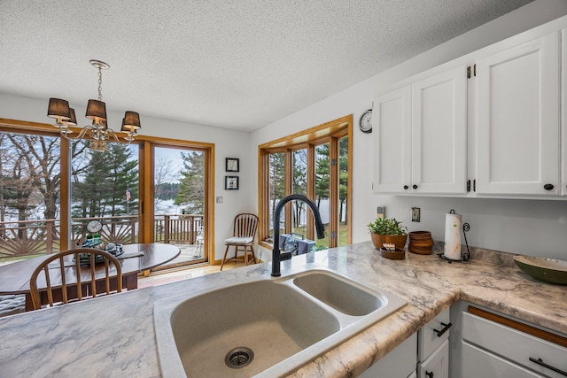 1171 County Rd E, Scott Twp, WI 54801 - kitchen with a sink, light countertops, a textured ceiling, a chandelier, and white cabinetry
