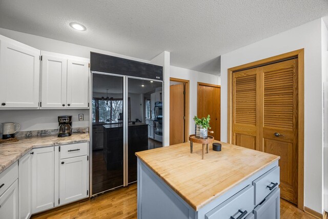 1171 County Rd E, Scott Twp, WI 54801 - kitchen with light wood finished floors, butcher block counters, white cabinets, and oven