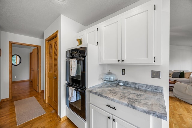 1171 County Rd E, Scott Twp, WI 54801 - kitchen featuring white cabinets, light stone countertops, dobule oven black, light wood-style flooring, and baseboards