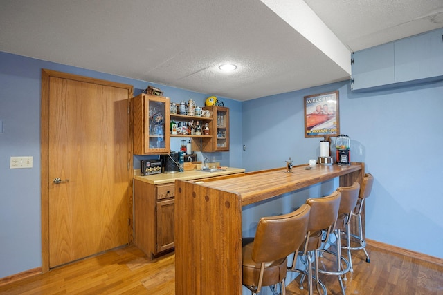 1171 County Rd E, Scott Twp, WI 54801 - bar with a textured ceiling, a sink, baseboards, indoor wet bar, and light wood finished floors