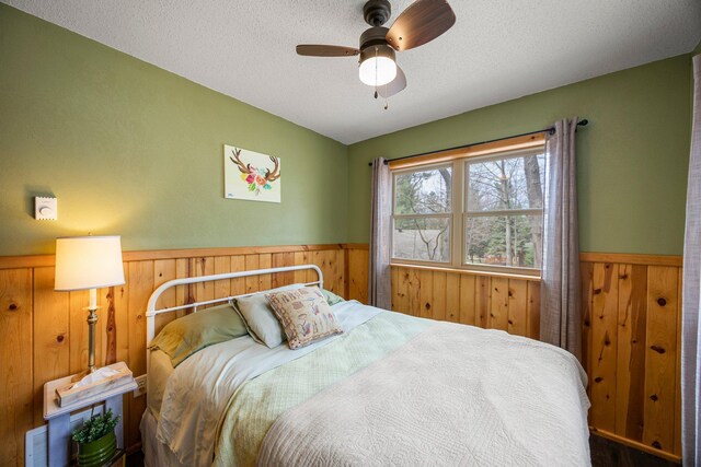 1171 County Rd E, Scott Twp, WI 54801 - bedroom featuring a textured ceiling, wood walls, wainscoting, and ceiling fan