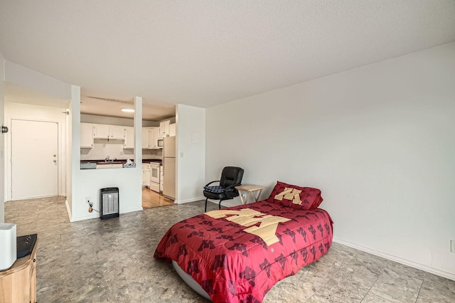 bedroom featuring a sink, baseboards, and freestanding refrigerator