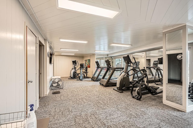 gym featuring carpet flooring and wood walls
