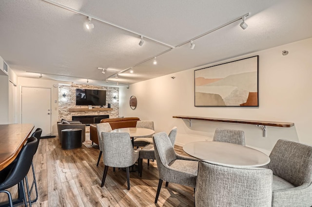 dining area featuring visible vents, rail lighting, wood finished floors, and a fireplace