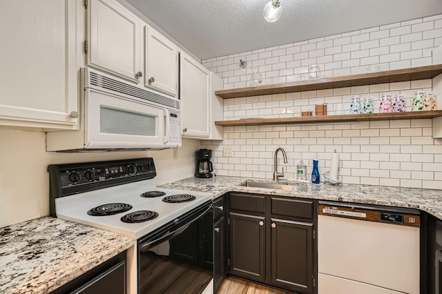 kitchen featuring open shelves, a sink, light wood finished floors, white appliances, and tasteful backsplash
