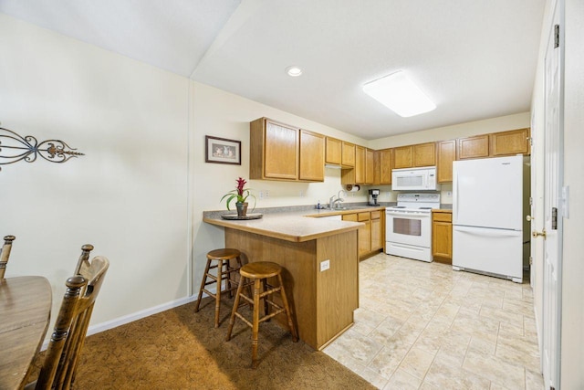 kitchen with white appliances, a peninsula, a kitchen bar, light countertops, and a sink