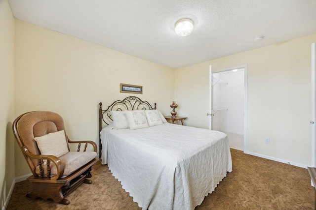 bedroom with carpet, baseboards, a textured ceiling, and a spacious closet