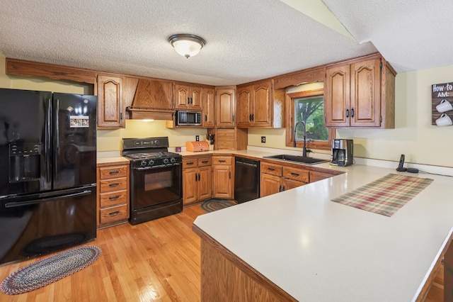 2060 Donnelly Dr NW, Maple Lake Twp, MN 55313 - kitchen with black appliances, a sink, a textured ceiling, a peninsula, and brown cabinetry